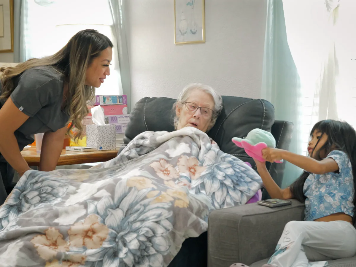 Caregiver and a visiting child with a resident in the living room at A Care Of Joy, University Place